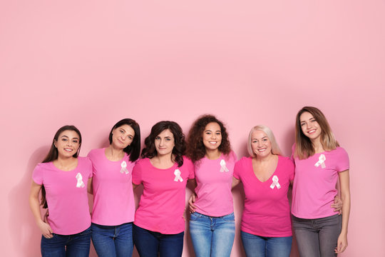 Group of women with silk ribbons on color background. Breast cancer awareness concept