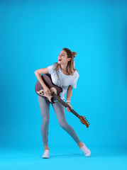 Fototapeta na wymiar Young woman playing electric guitar on color background