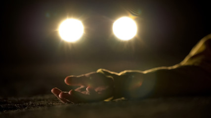 Bloody murderer driving on lifeless body of victim lying on road, terrible crime