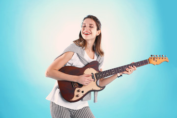 Fototapeta premium Young woman playing electric guitar on color background