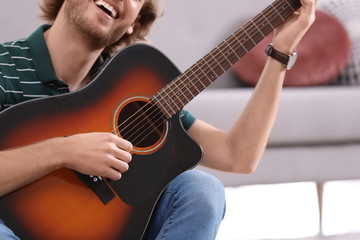 Obraz premium Young man playing acoustic guitar at home, closeup