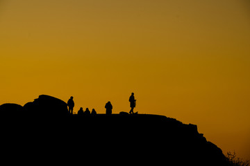 silhouette of people on top of a mountain at sunset with orange sky