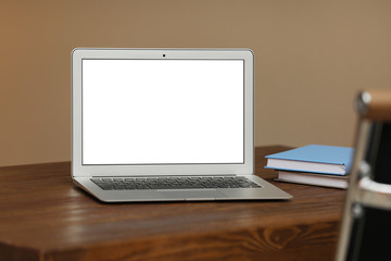 Laptop with blank screen on table indoors. Space for text