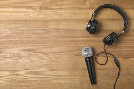 Headphones, microphone and space for text on wooden background, top view