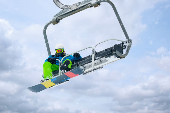 Snowboarder using ski lift at mountain resort. Winter vacation