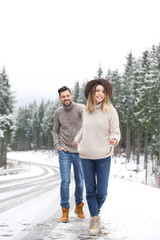 Fototapeta na wymiar Couple walking near snowy forest. Winter vacation