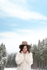 Fototapeta premium Young woman in warm sweater near snowy forest. Winter vacation