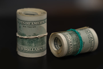 Two rolls of USD banknotes on black