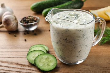 Cucumber sauce with ingredients on wooden background, space for text. Traditional Tzatziki