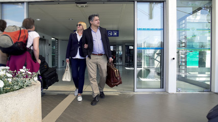 Adult couple leaving airport, people arriving on vacation, family holidays
