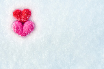 Valentine's day background with red and pink wool felted hearts lying on the white snow
