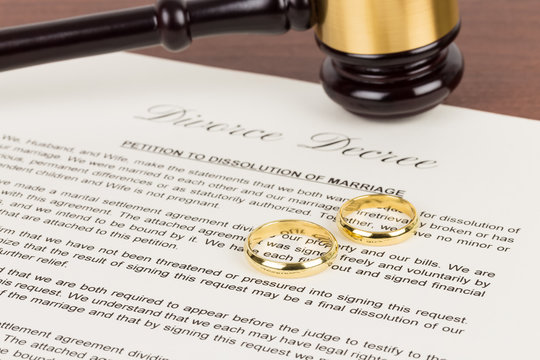 Wooden judge gavel, golden rings, and divorce decree; document is mock-up