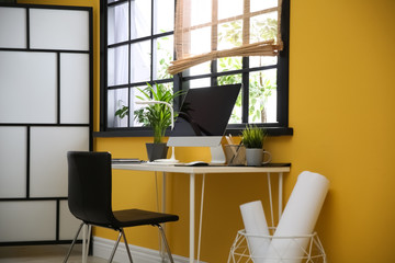 Stylish workplace with computer near window at home office. Space for text