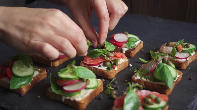 Chef preparing canape sandwiches with vegetables, cheese and basil