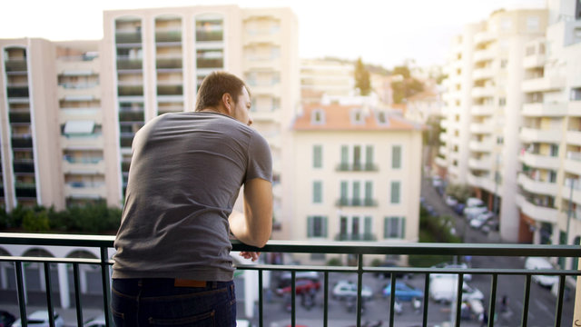 Man Enjoying View From His Hotel Suite Balcony On Busy Street, Business Trip