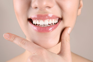 Beautiful young woman with healthy teeth on color background, closeup