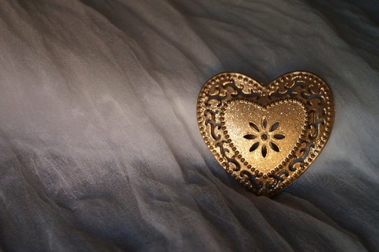 Heart of golden metal on a silk background