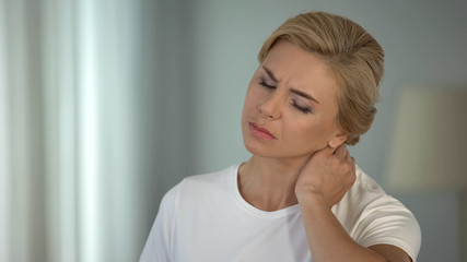 Good-looking blond woman suffering neck pain, sedentary life, health problems