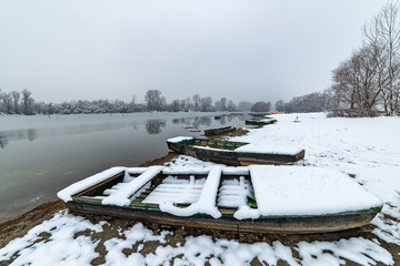 Danube island (Šodroš) near Novi Sad, Serbia. Colorful landscape with snowy trees, beautiful frozen river. A boats covered with snow or submerged.