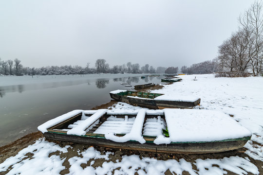 Danube island (&Scaron;odro&scaron;) near Novi Sad, Serbia. Colorful landscape with snowy trees, beautiful frozen river. A boats covered with snow or submerged.