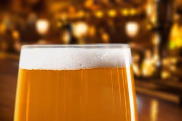 Glass of light beer on a dark pub