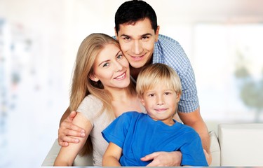 Beautiful smiling family sitting at sofa on background