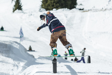 Snowboarder making freestyle trick on rail in the mountains 
