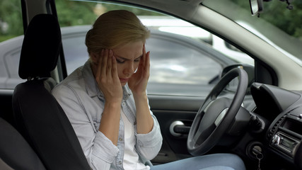 Blond female suffering from strong migraine, sitting in auto, headache disorder