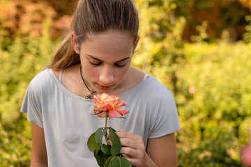 Maedchen riecht an einer Rose im Rosengarten 'La Rosaleda' im Parque del Retiro, Madrid, Spanien