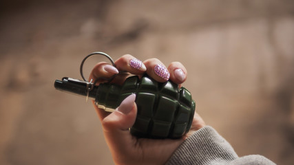 Women's hand with rhinestones on the nails holding a grenade