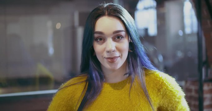 Confident blue hair woman with piercings smiling portrait.Freelancer,small business owner or student at studio office, coworking or school.People wearing casual.Modern,growth,success.4k video