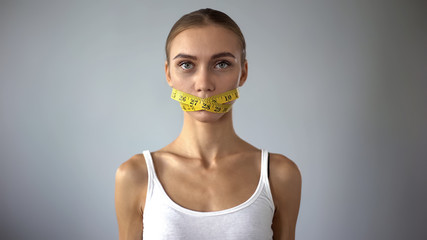 Lady with tape closing mouth looking at camera, weight loss calculating calories - obrazy, fototapety, plakaty