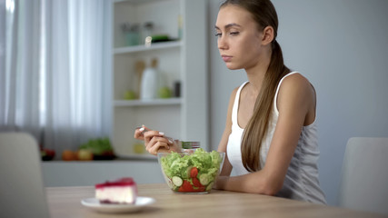 Slim girl eating salad but craving cake, fashion trend to be slender, diet