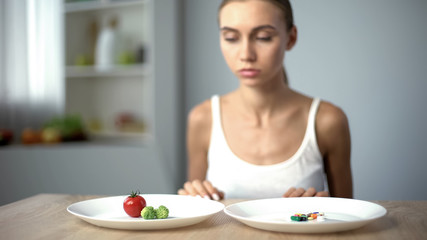 Obraz na płótnie Canvas Girl chooses vegetables instead of weight loss drugs, healthy diet, organic food