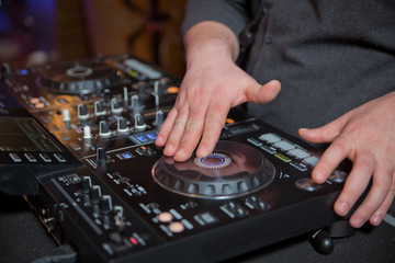 DJ's hands at the music mixer at a party - playing some fine songs for the guests color toned image...