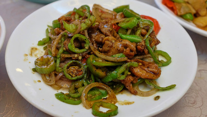 Beef with Green Pepper on a white square plate on a table