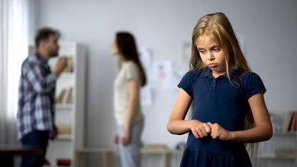 Frightened girl nervously twisting fingers, scared by parents quarrel, violence