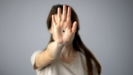 Obraz na płótnie Canvas Black dot on womans hand, secret sign of domestic violence victim, support