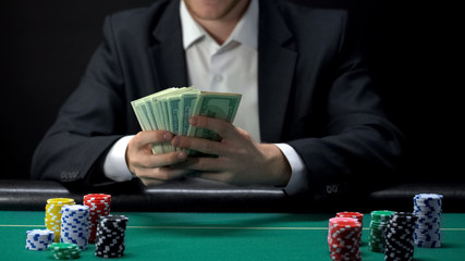 Lucky casino winner holding dollar banknotes, chips on table around, game award