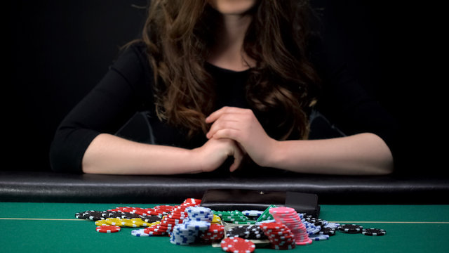 Beautiful female gambler betting all casino chips and money in risky poker game