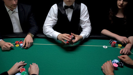 Male croupier holding cards ready to start poker game at casino, gambling sports