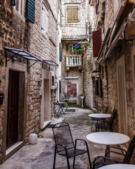 Fototapeta na wymiar narrow street branch between historic buildings built of stones, windows with wooden closures