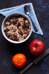 Bowl with muesli, an apple and tangerine with a spoon and a knife viewed from above