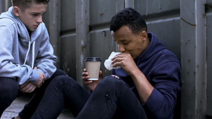 Volunteer treating afro-american homeless with free lunch, kindness and charity