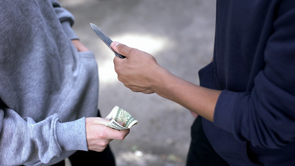 Teenager threatening boy with knife, extorting money, street robbery, closeup