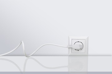 White electrical plug in the electric socket on a wall