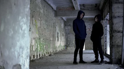 Foto op Aluminium Boys in hoodie talking in ruined building, teenage gang, young criminals © motortion