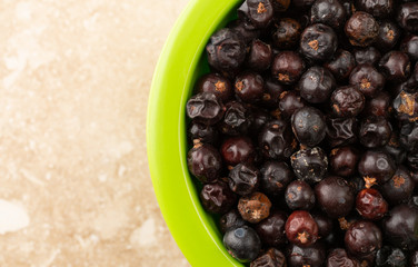 Bowl filled with juniper berries on a marble counter top close view