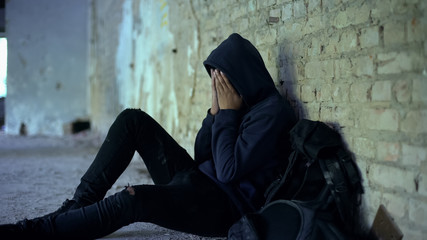 Miserable teenager crying in abandoned house, life destroyed by war, sorrow