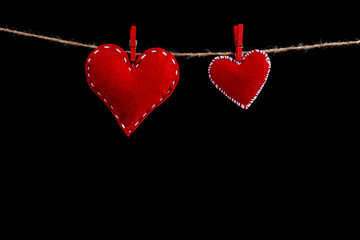 Two red felt hearts on a rope. Handmade blank for greeting card, copy space, isolate on black background.